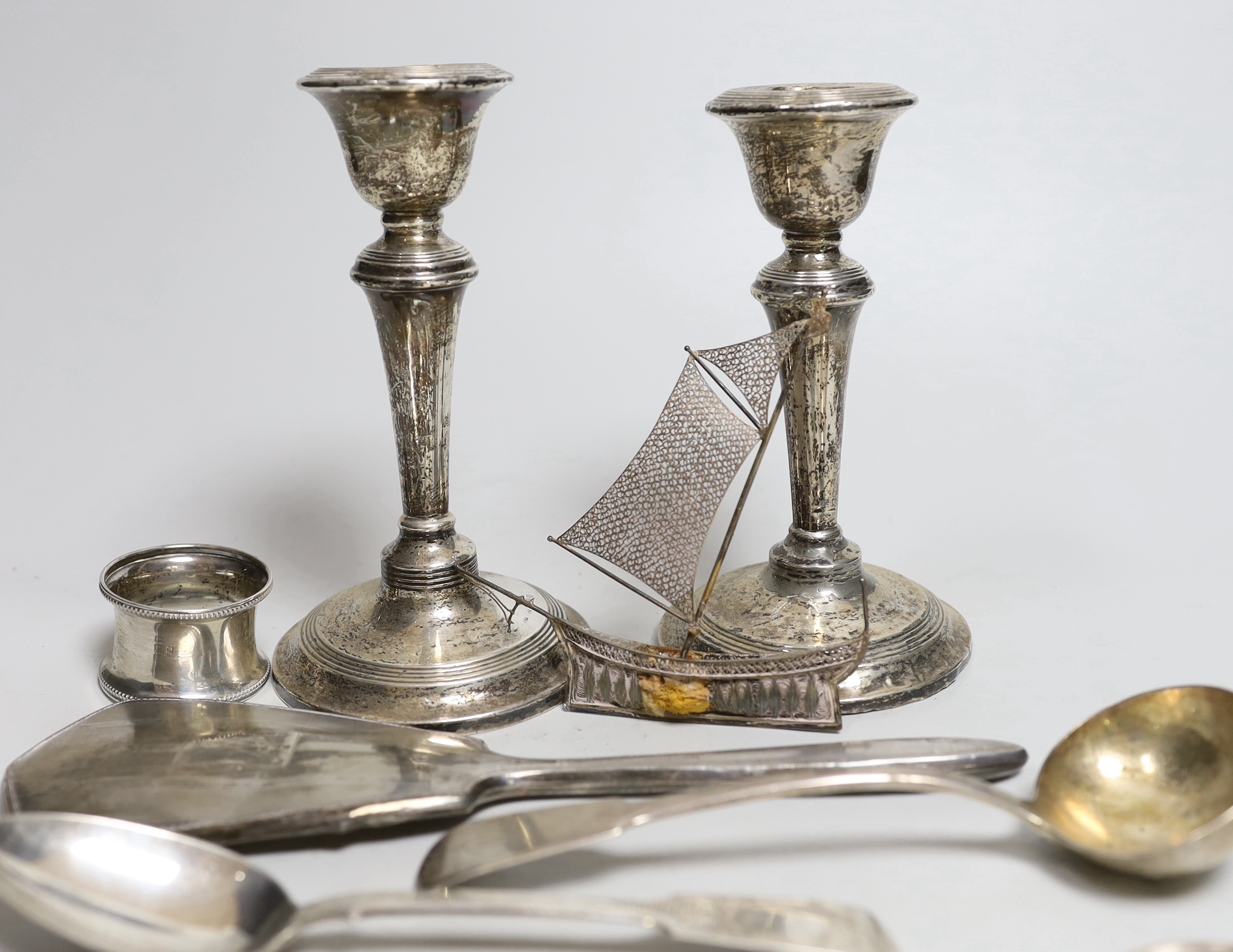 A pair of Edwardian silver candlesticks, Birmingham, 1909, 15.2cm (a.f.) a George IV silver sauce ladle and other items including a napkin ring and two silver spoons.